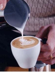 latte art milchschaum wird in tasse gegossen