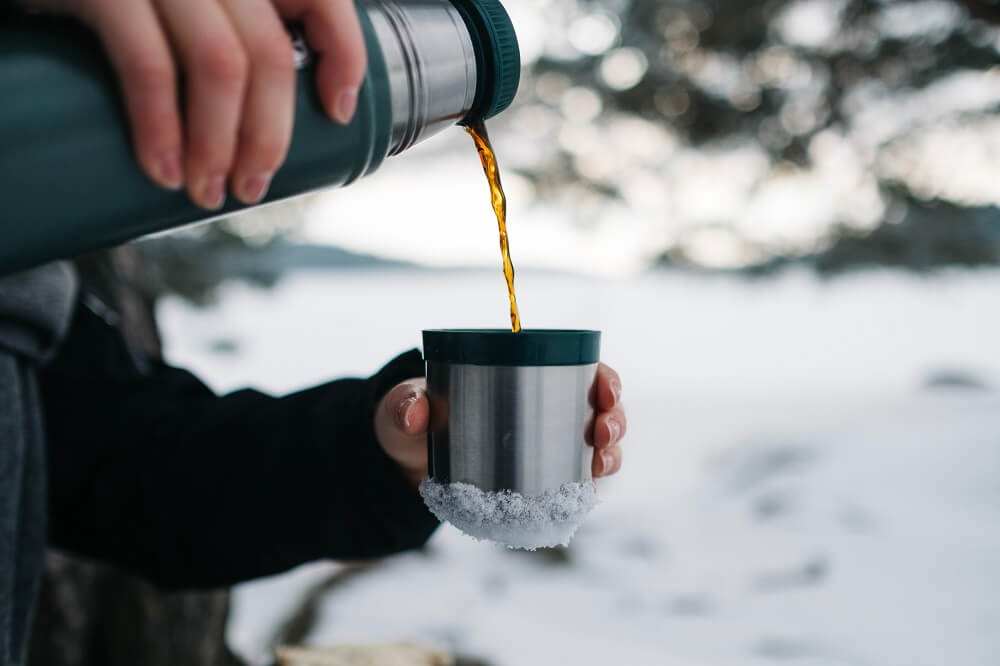 Thermoskanne Kaffee eingießen in Tasse