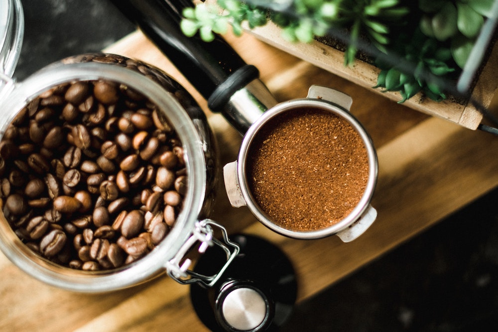 Kaffebohnen im Glas und Topfpflanze