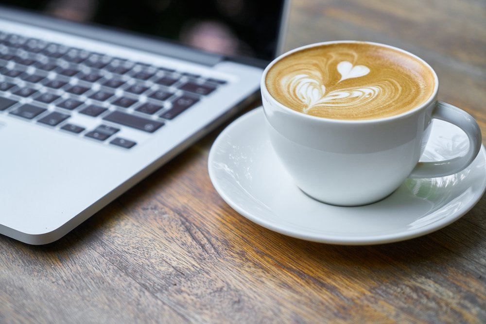 Cappuccino aus Vollautomat neben Laptop