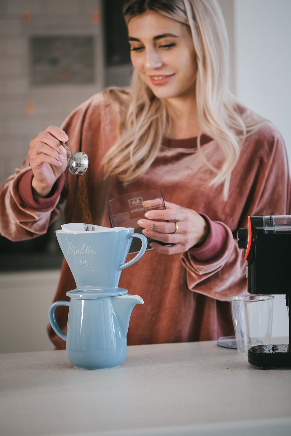 Frau die Filterkaffee zubereitet mit Melitta® Kaffeebereiter in eisblau Frau die Filterkaffee zubereitet mit Melitta® Kaffeebereiter in eisblau