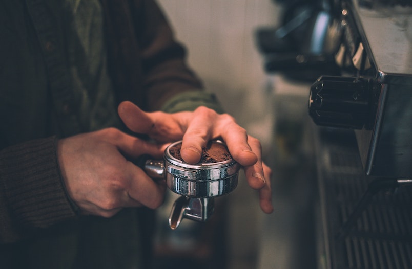 Kaffeemehl wird im Siebträgerhalter angedrückt